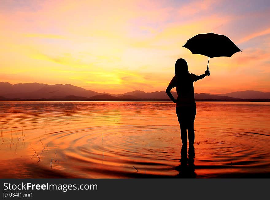 Silhouette of young woman wading in sea at sunset. Silhouette of young woman wading in sea at sunset