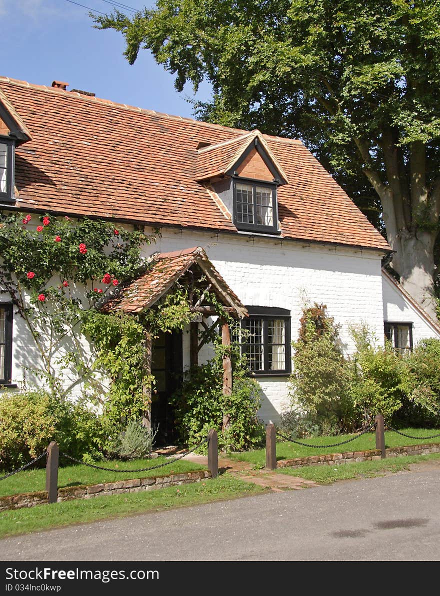 Traditional whitewashed English Village Cottage  with roses on the wall. Traditional whitewashed English Village Cottage  with roses on the wall