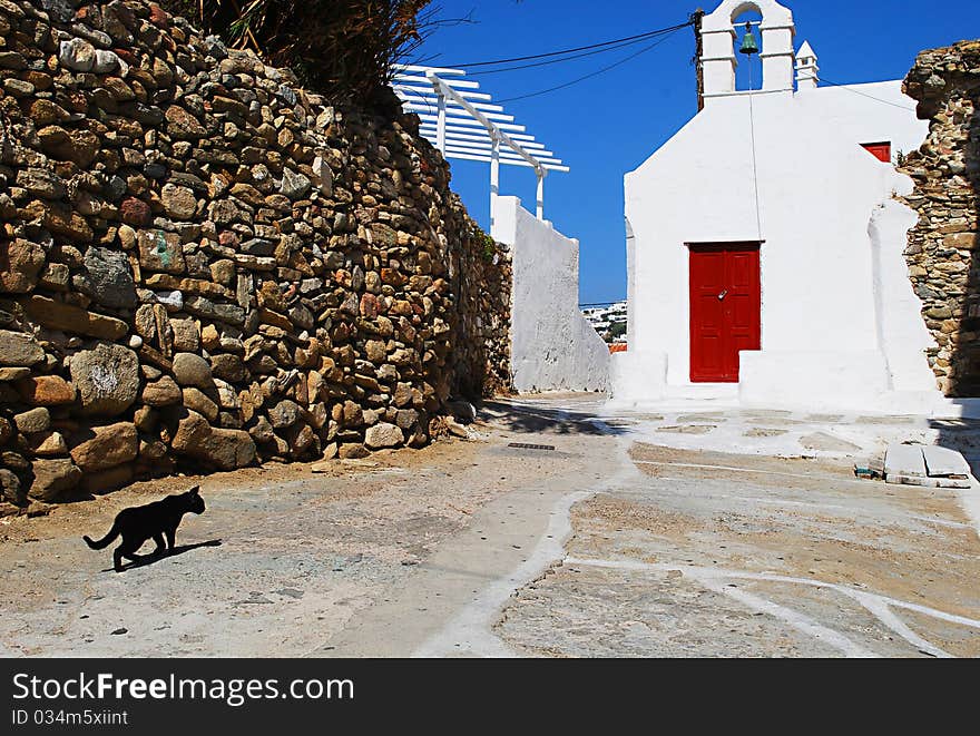 Black Cat walking in a street at Mykonos during summer. Black Cat walking in a street at Mykonos during summer