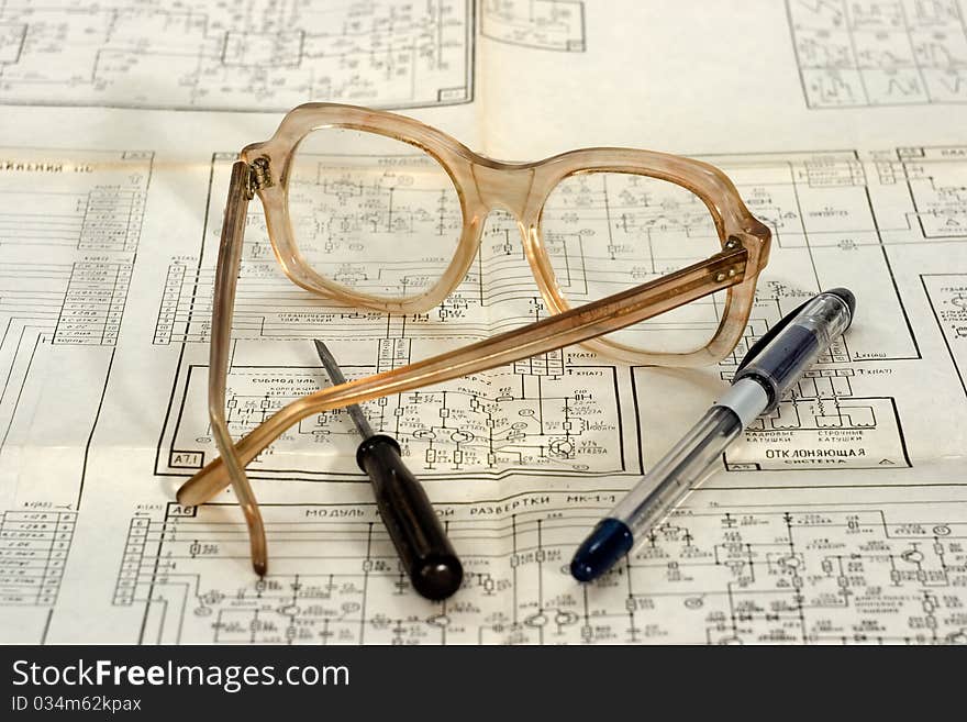 Glasses screwdriver pencil lie on the scheme of an electronic device. Glasses screwdriver pencil lie on the scheme of an electronic device.