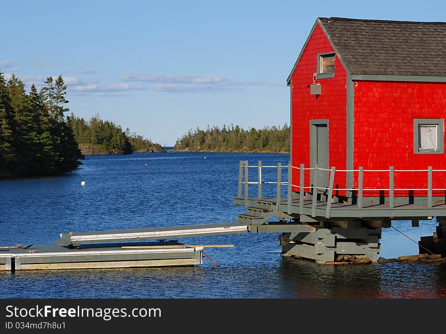 A red building is sits near the water. A red building is sits near the water