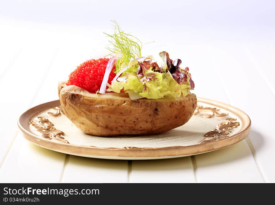 Baked potato and red caviar garnished with lettuce. Baked potato and red caviar garnished with lettuce