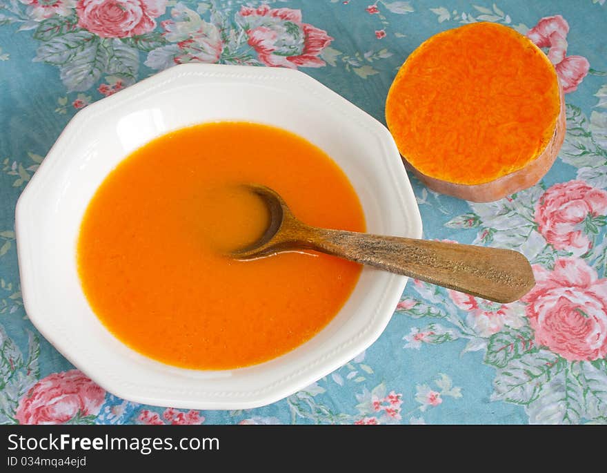 Creamy pumpkin soup in ceramic boil and fresh pumpkin