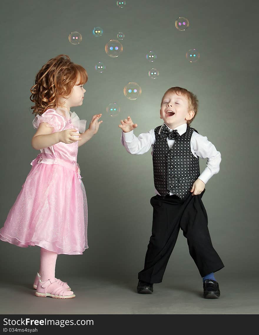 The boy and the girl cheerfully play with soap bubbles. The boy and the girl cheerfully play with soap bubbles