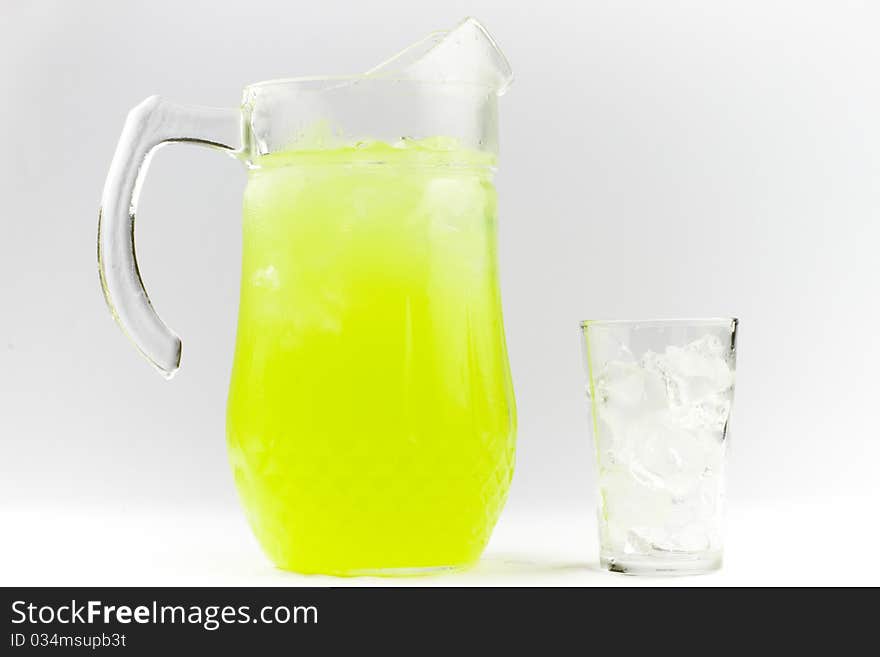 Lime flavoured cold drink in a glass jug next to a glass of ice. Lime flavoured cold drink in a glass jug next to a glass of ice