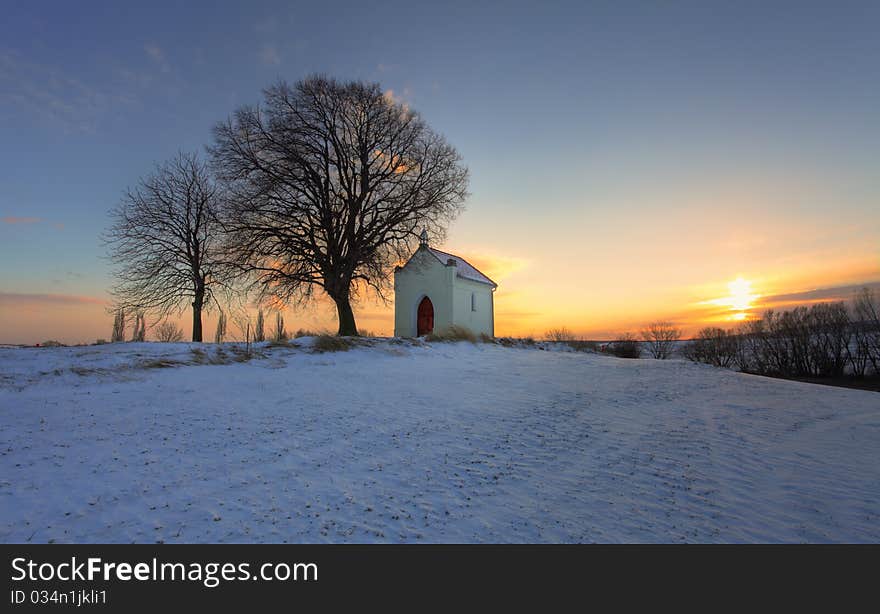 Sunset On Frozen Field With A Chapel