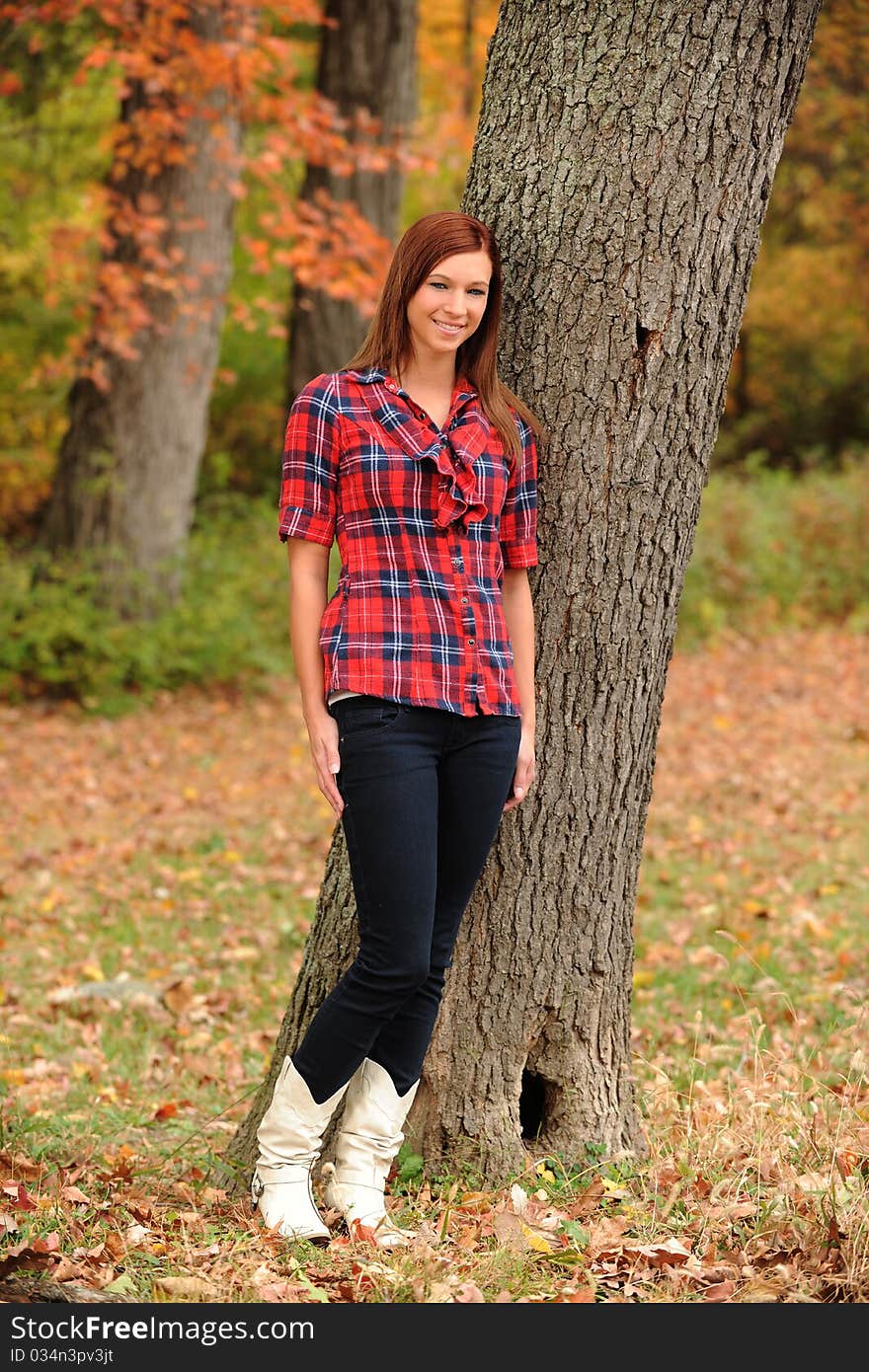 Young Woman standing by a tree on a fall day