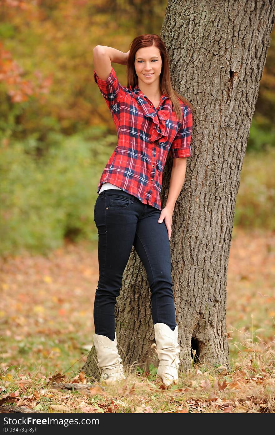 Young Woman standing by a tree on a fall day