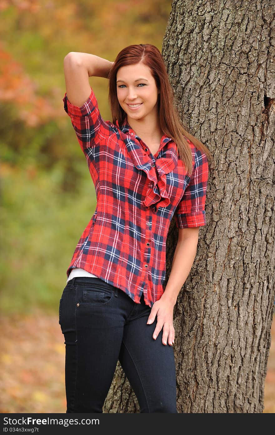 Young Woman standing by a tree on a fall day