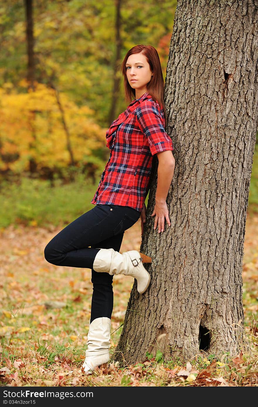 Young Woman standing by a tree on a fall day