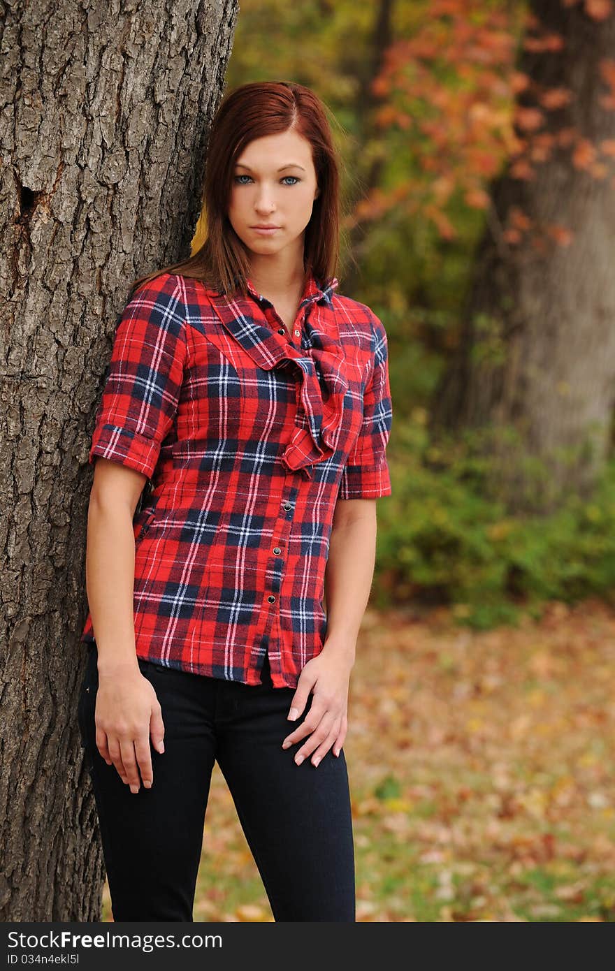 Young Woman standing by a tree on a fall day