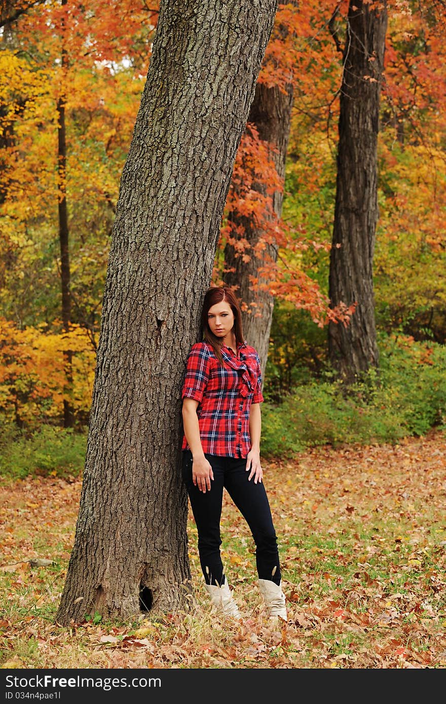 Young Woman standing by a tree on a fall day