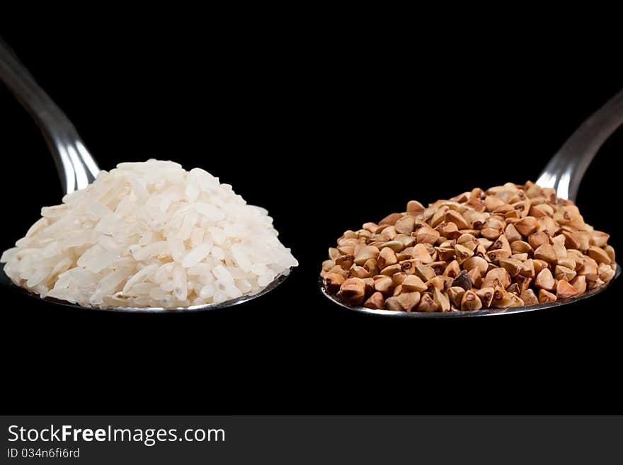 Rise and buckwheat on spoons with black isolated background