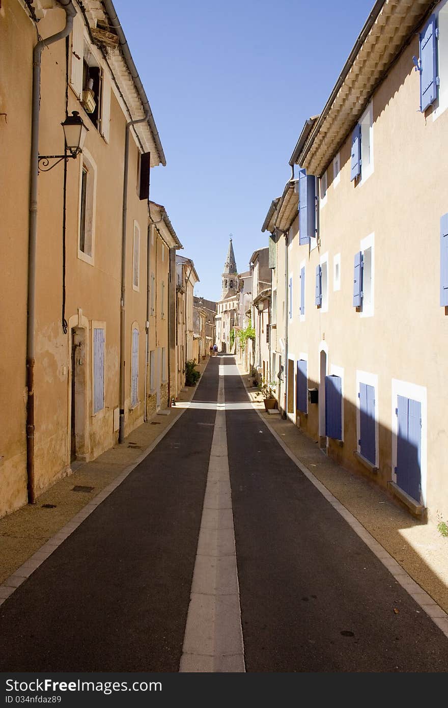 Residential street in Provence, straight and converging with church at the end