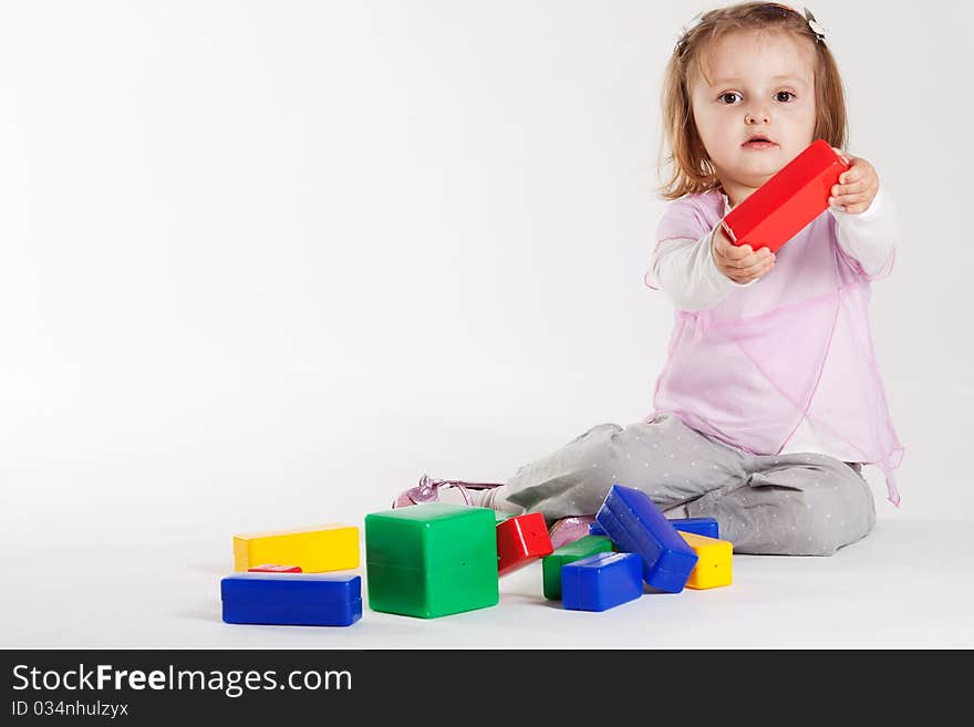 Little girl plays with cubes on white background