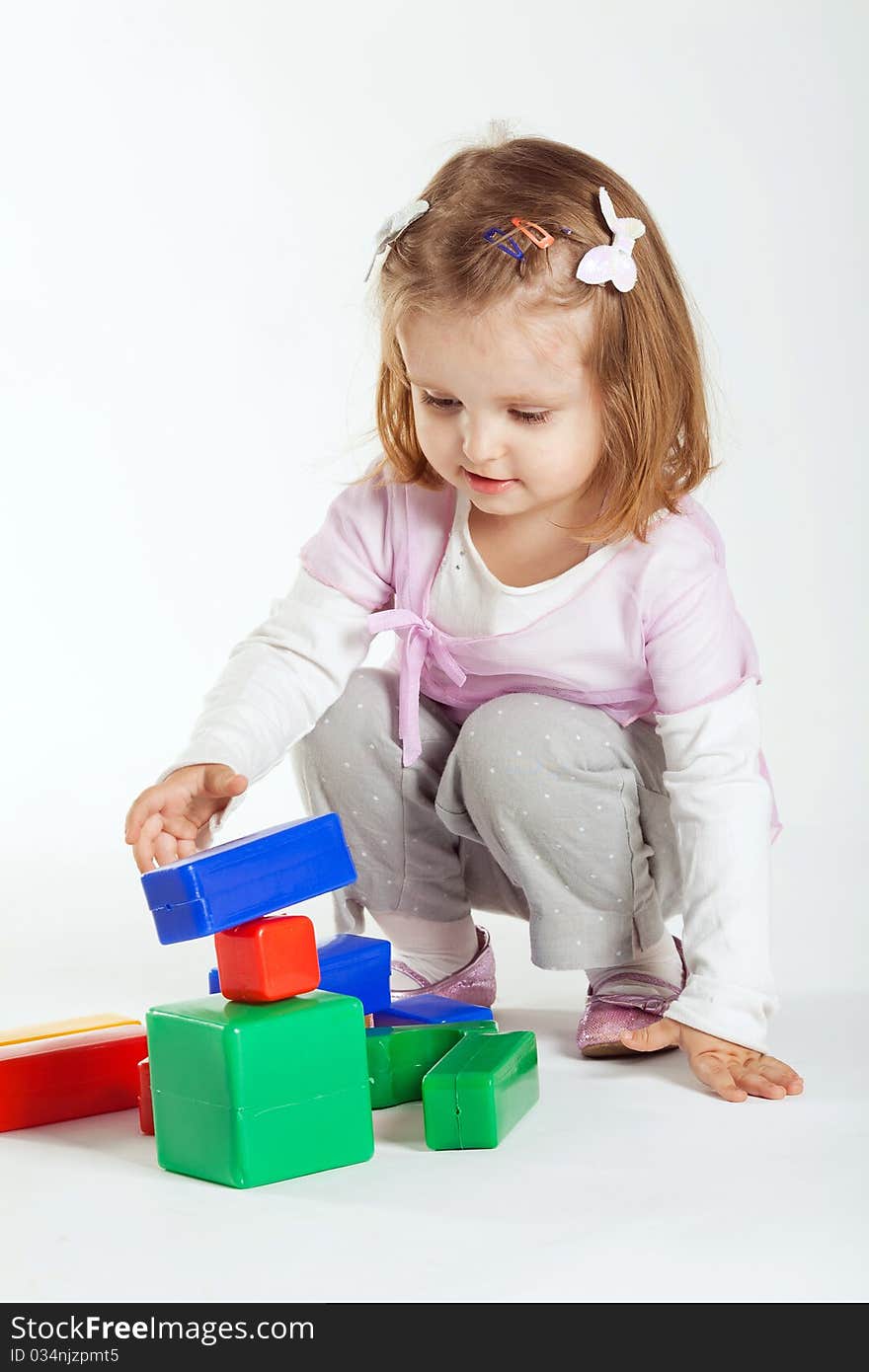 Little girl plays with cubes on white background