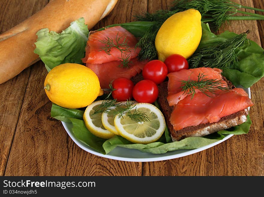 Salmon sandwiches on a plate with lettuce and served with lemon slices