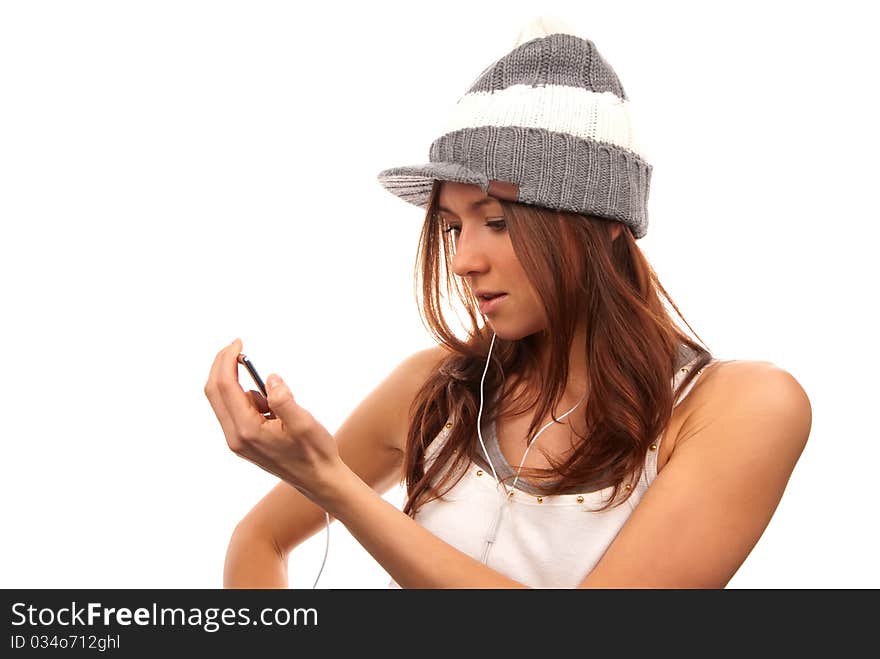 Pretty young female looking and reading text message on her new modern cell phone mobile and listening music in headphones isolated on a white background. Pretty young female looking and reading text message on her new modern cell phone mobile and listening music in headphones isolated on a white background