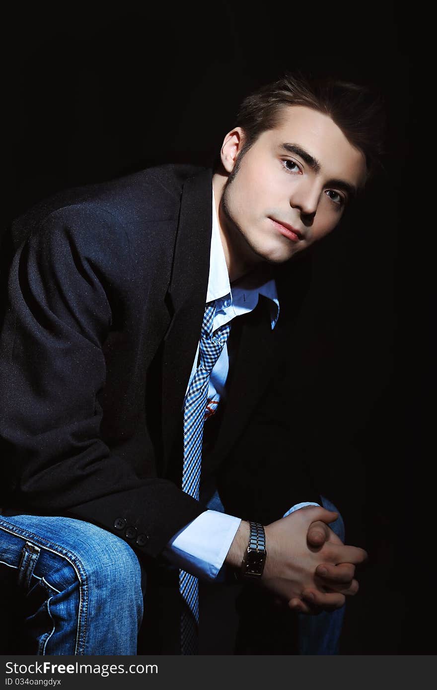 Portrait of a young businessman posing over black background.