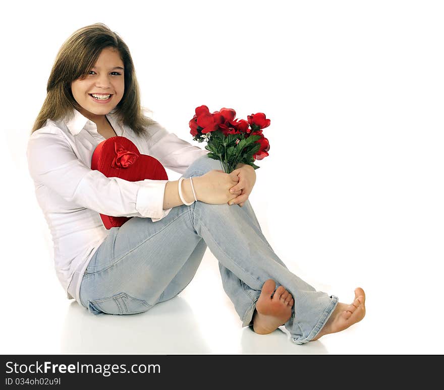 A casual, young teen girl delighted with a gift of red roses and a heart-shaped box chocolates. Isolated on white. A casual, young teen girl delighted with a gift of red roses and a heart-shaped box chocolates. Isolated on white.