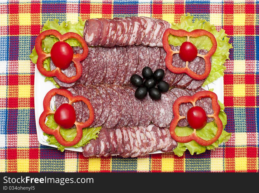 Sliced sausage on a plate with bright vegetables. Sliced sausage on a plate with bright vegetables