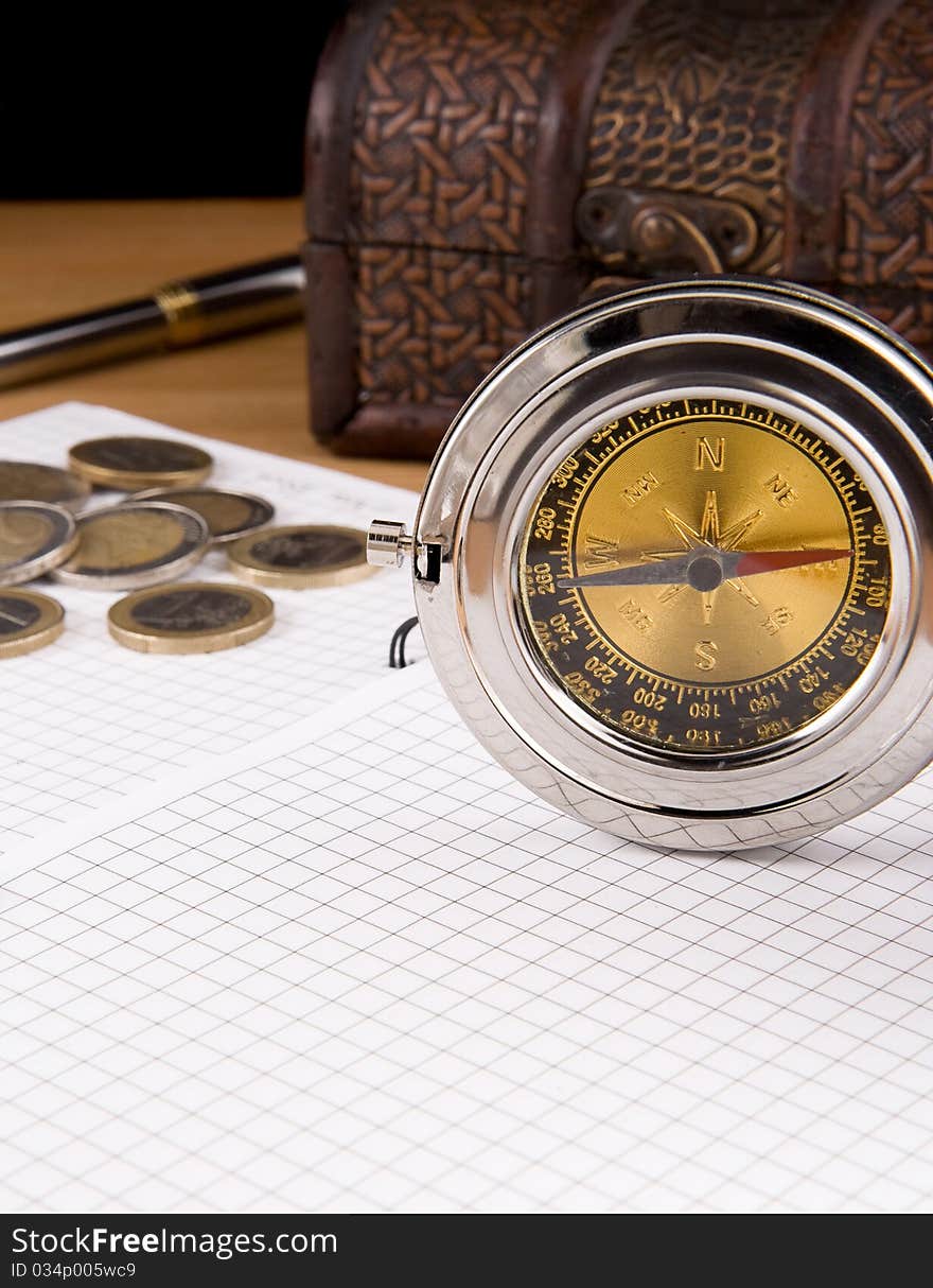 Compass, pen and coin on checked notebook. Compass, pen and coin on checked notebook