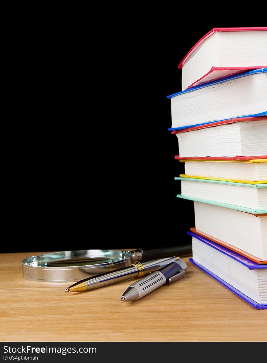 Pile of books and pen on black background