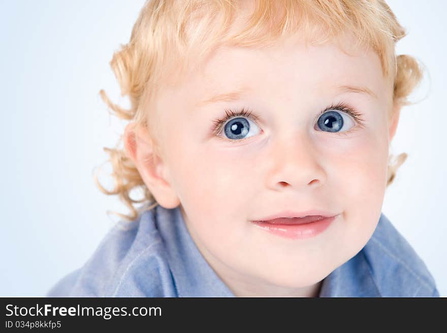 Close up portrait of a smiling happy little toddler isolated over a light blue background. Close up portrait of a smiling happy little toddler isolated over a light blue background