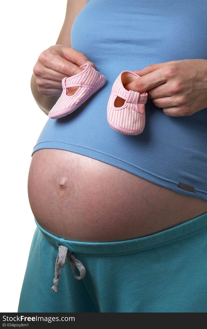 Pregnant woman profile with tiny shoes in the hands over white background. Pregnant woman profile with tiny shoes in the hands over white background