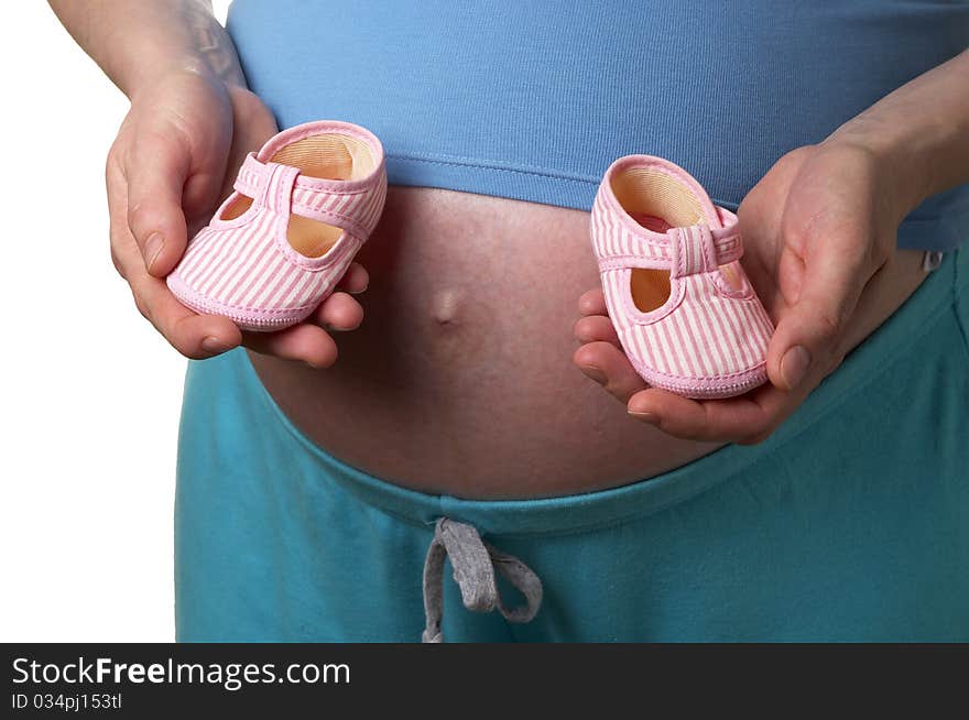 Pregnant woman profile with tiny shoes in the hands over white background. Pregnant woman profile with tiny shoes in the hands over white background