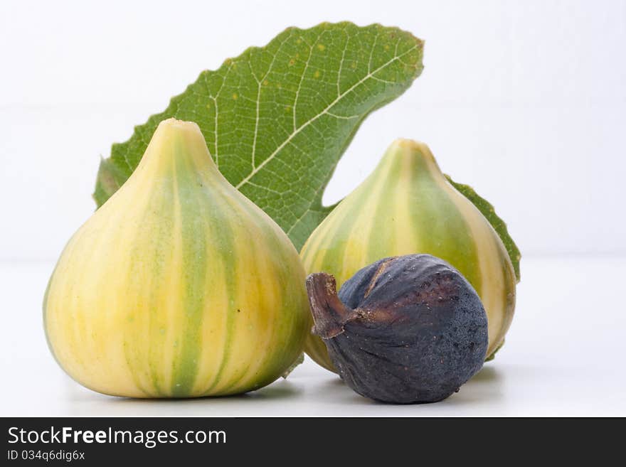 Ripe fruits of a fig on a white surface.