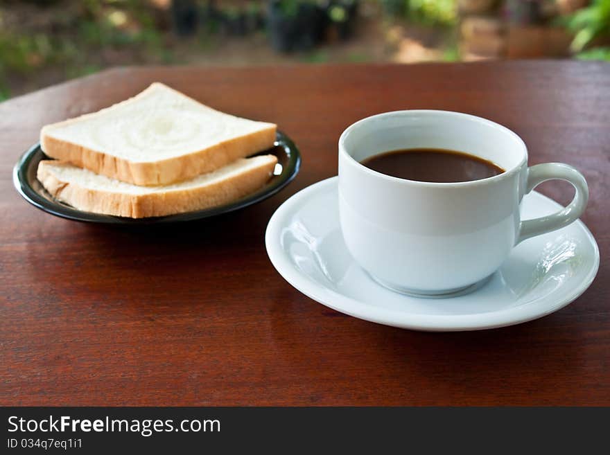 Cup of coffee and bread on table