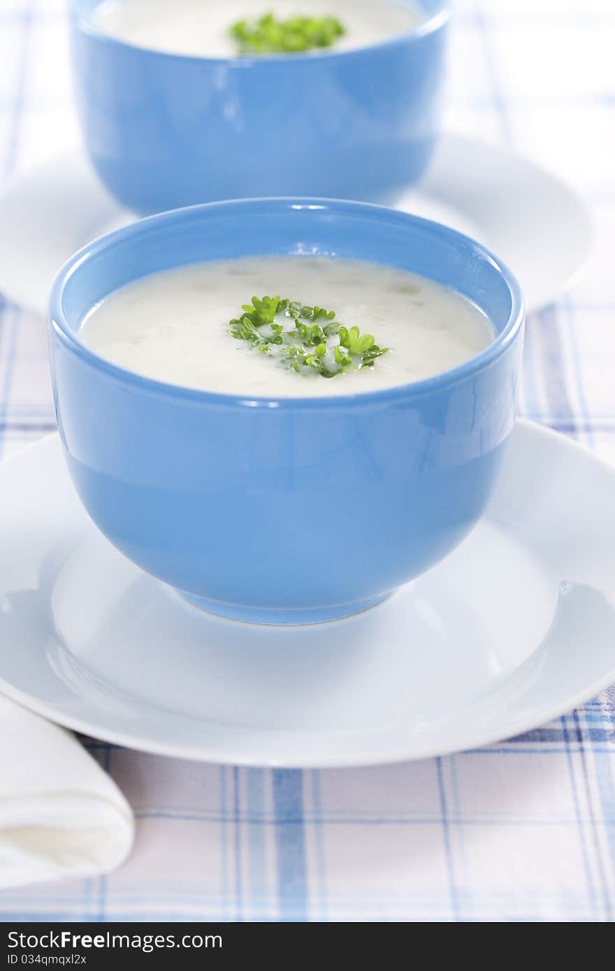 Two blue bowls of onion pureed soup with parsley