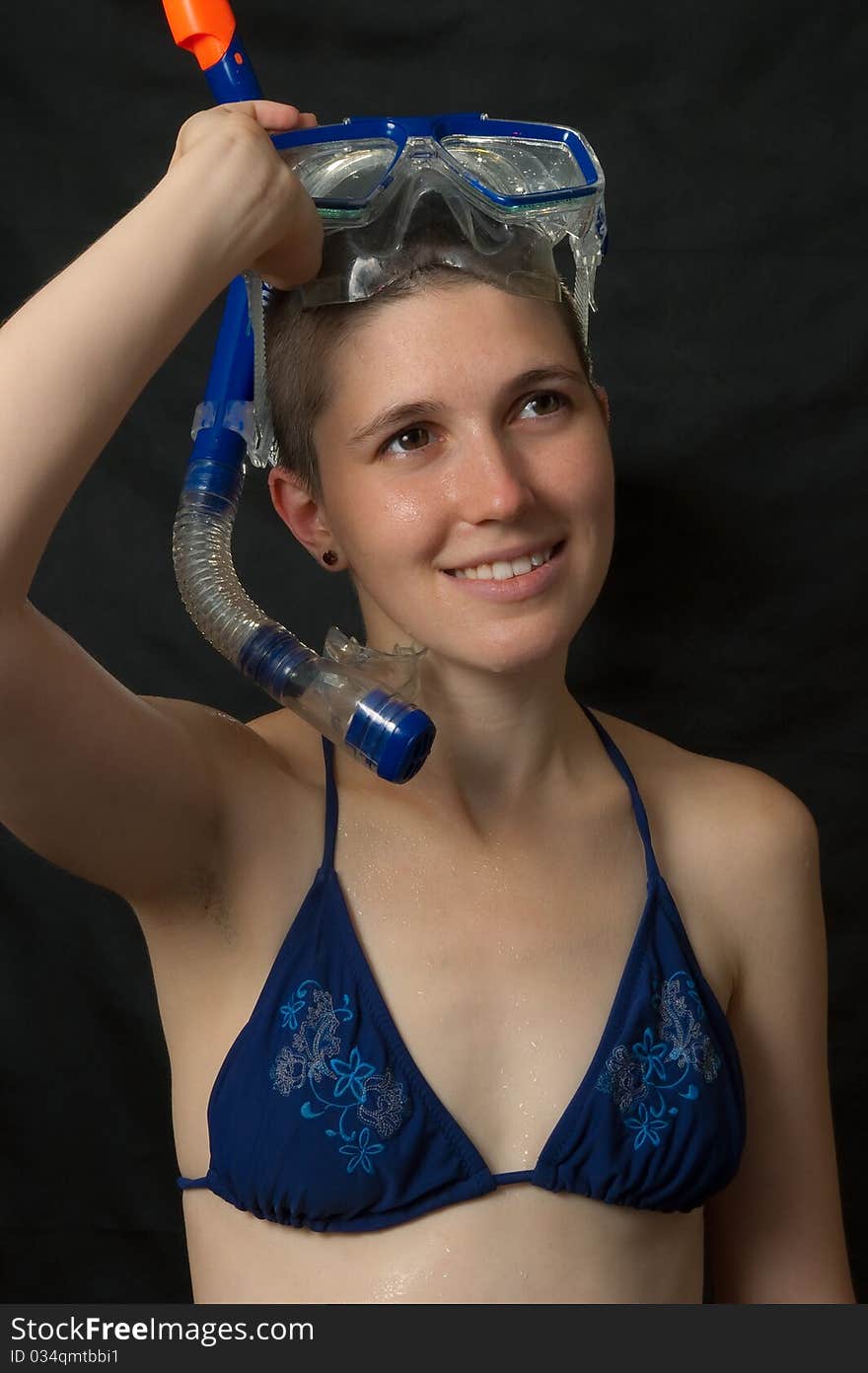 Smiling girl with diving mask in bikini isolated on black