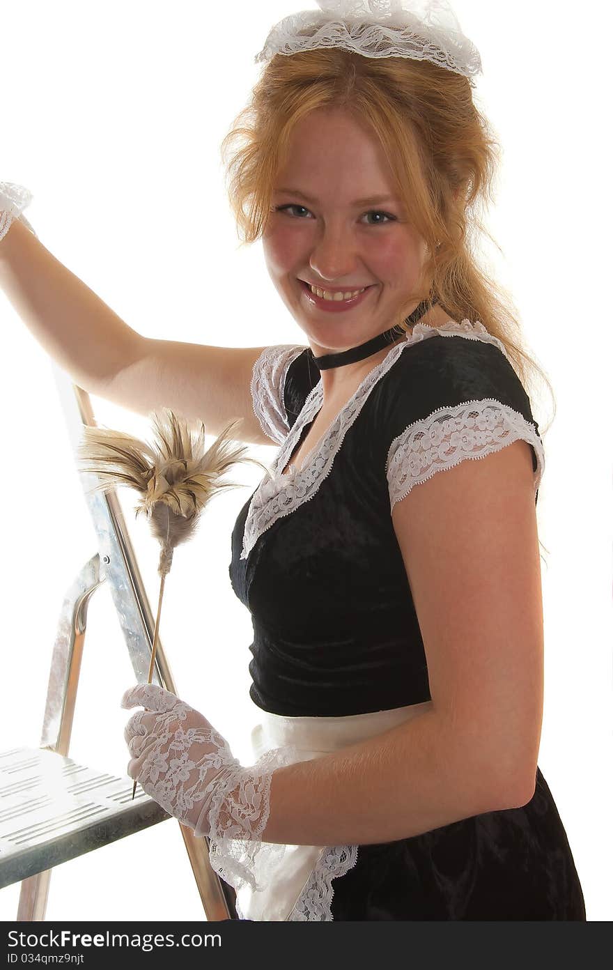 Smiling maid with a feather duster on a ladder isolated on white