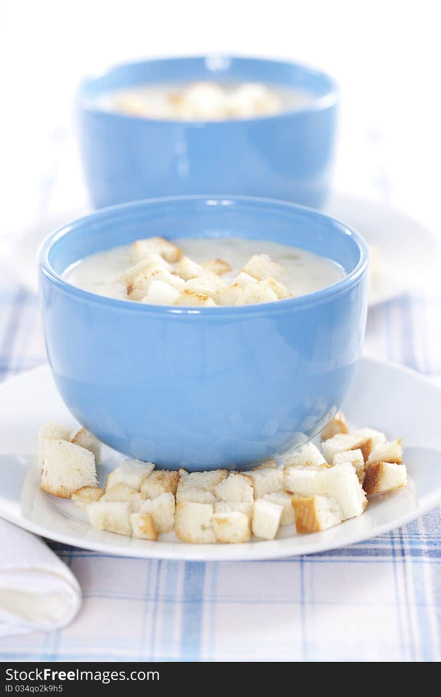 Two blue bowls of onion pureed soup with croutons