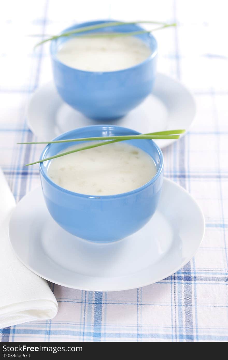 Two blue bowls of onion pureed soup with leek