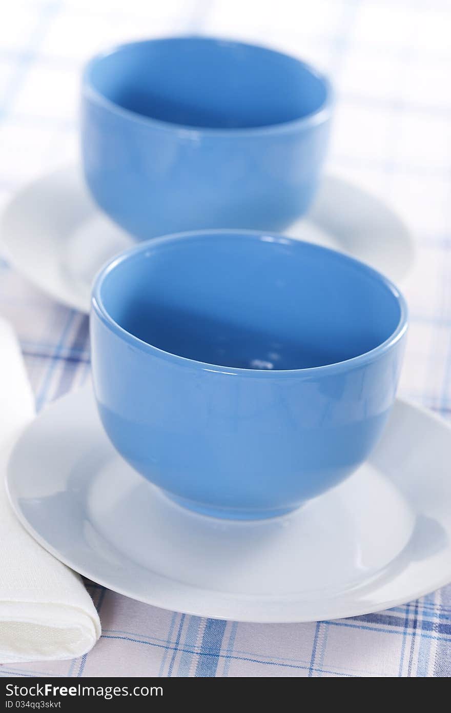 Two empty blue plates for the soup on a checkered tablecloth