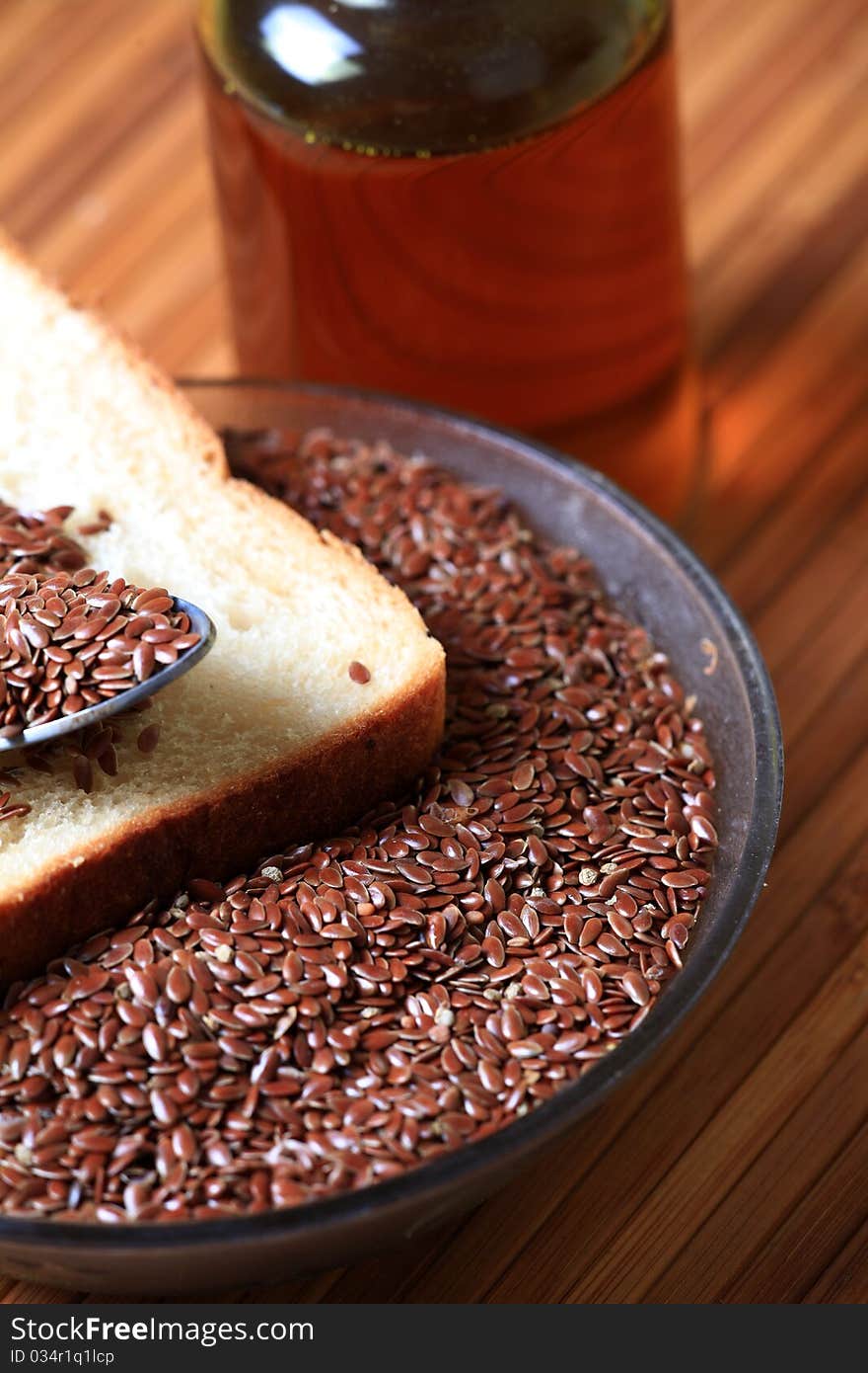 Closeup shot of bowl of raw linseed's with brown bread slice over wooden background. Closeup shot of bowl of raw linseed's with brown bread slice over wooden background.