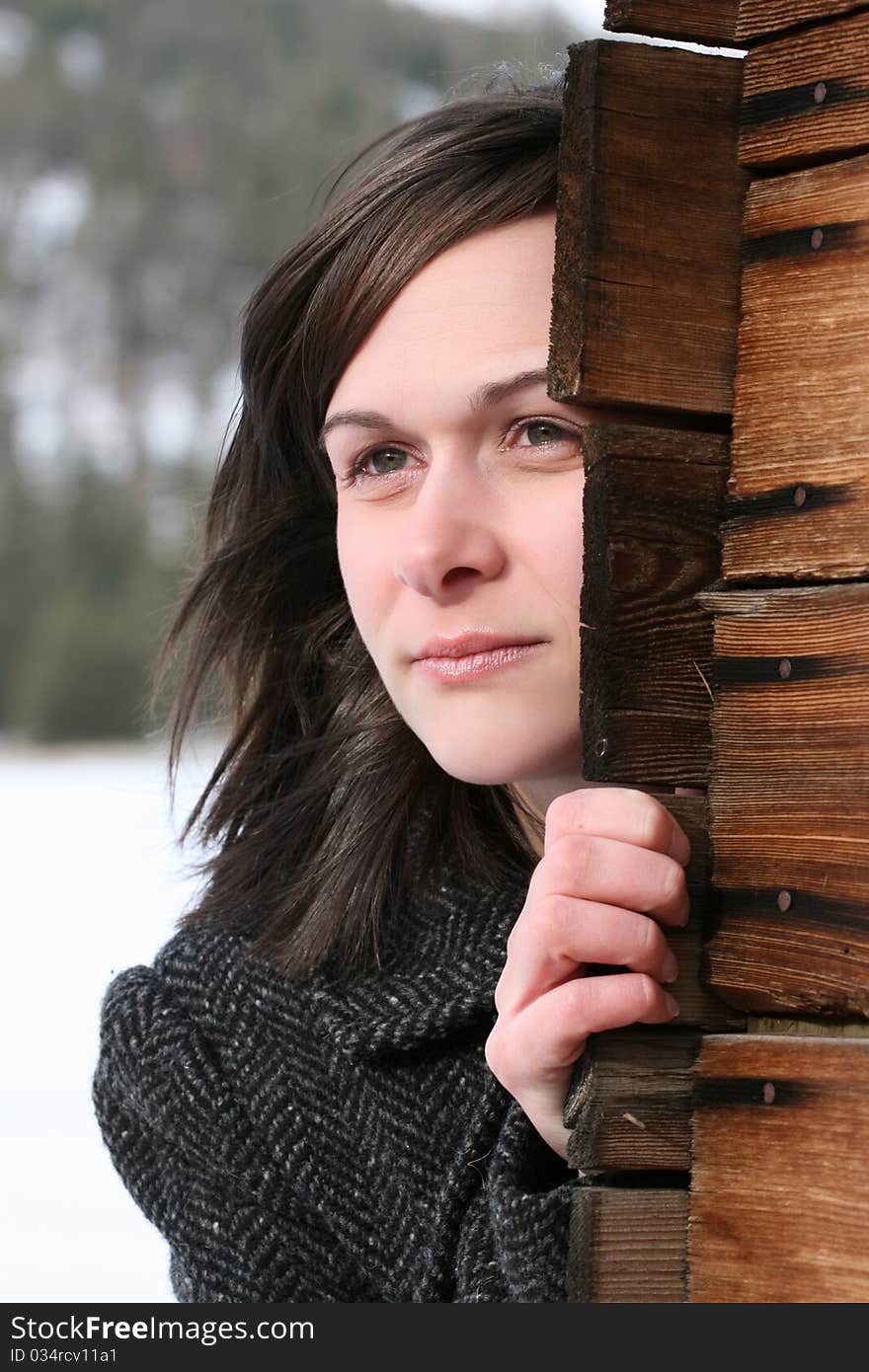 Beautiful brunette female leaning against wooden barn