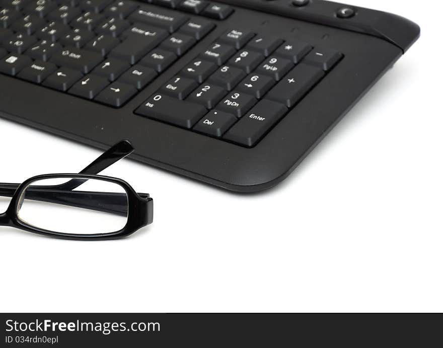 Glasses on computer keyboard isolated on white background