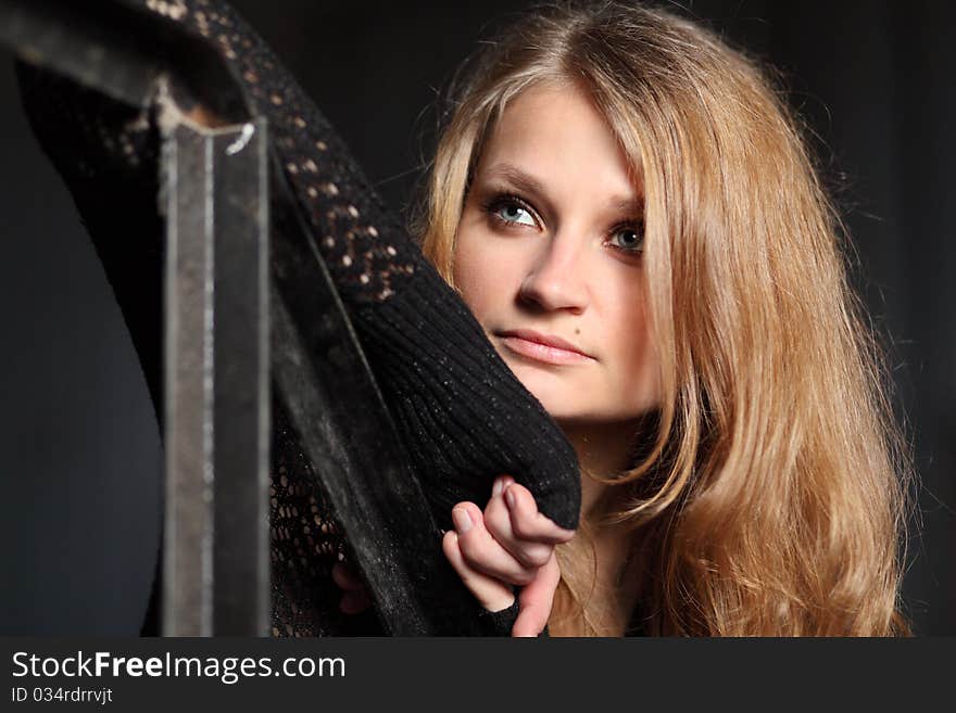 Young blond woman in black leans on  handrail. Young blond woman in black leans on  handrail