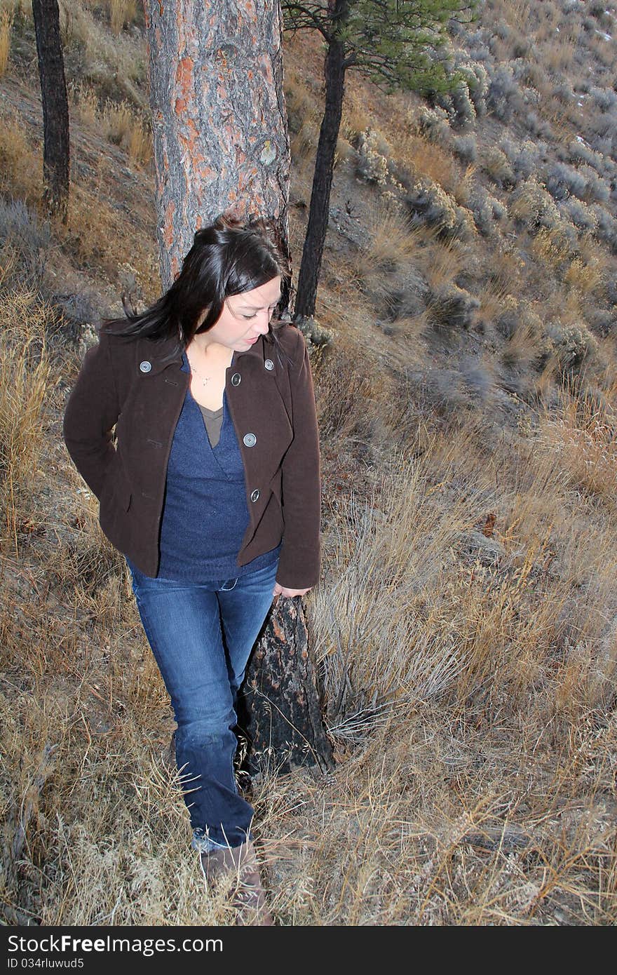 Mature brunette female leaning against a tree