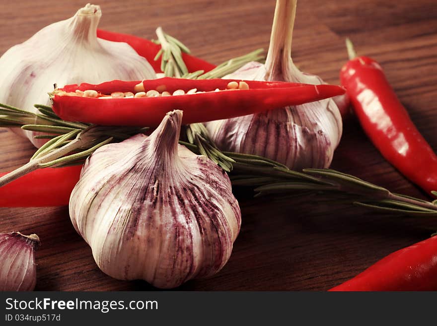 Fresh garlic with red pepper and rosemary on a table. Fresh garlic with red pepper and rosemary on a table.