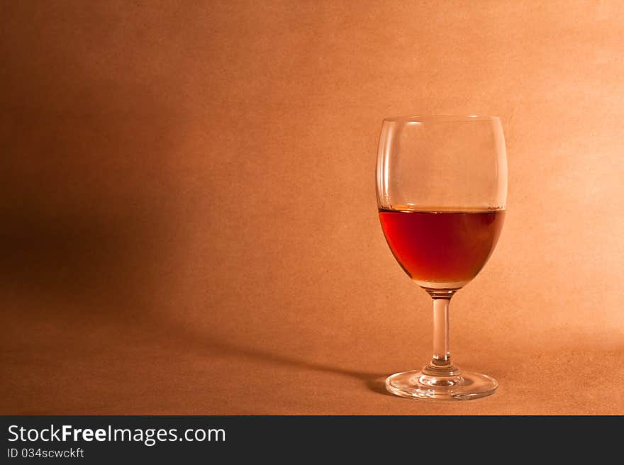 Elegant red wine glass on brown wooden background