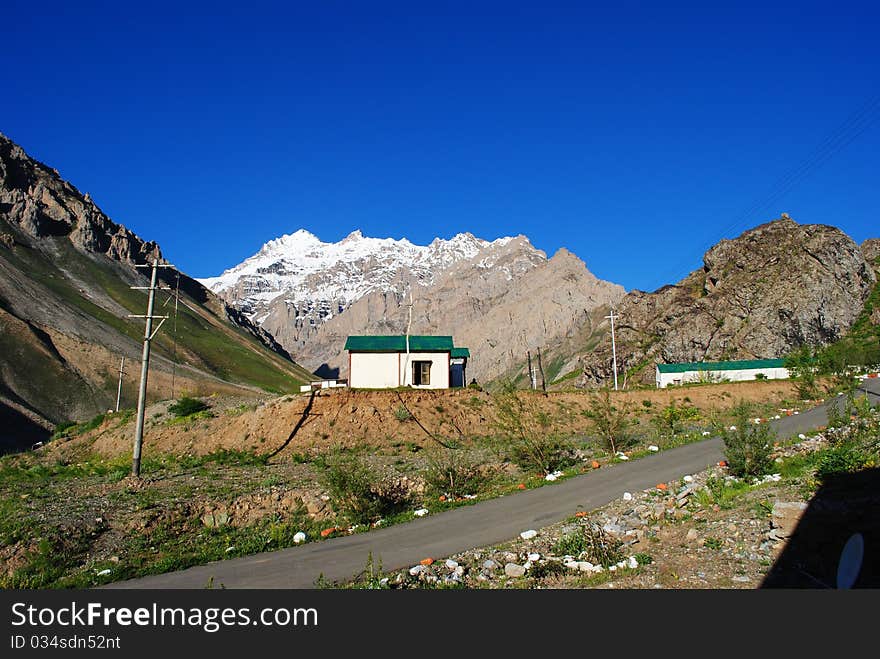 A beautiful landscape with a blue sky and a small road leading to a mountain. A beautiful landscape with a blue sky and a small road leading to a mountain.