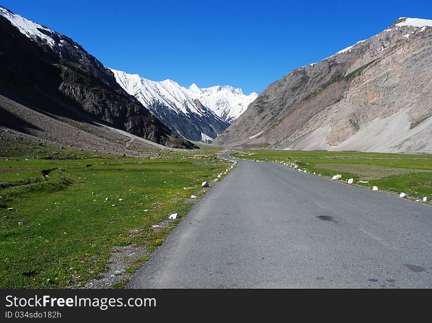 A road leading to a distant snow peak in a Himalayan valley. A road leading to a distant snow peak in a Himalayan valley.