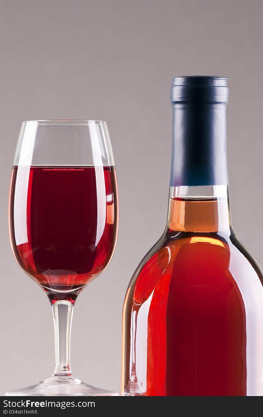 Glass and bottle of rose wine with gray background