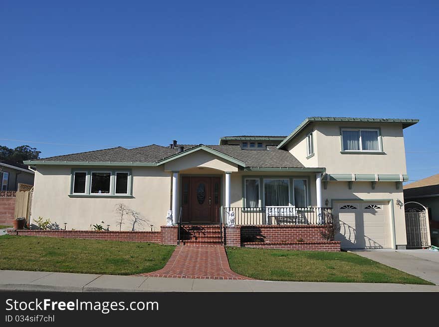 House surrounded by trees and grass with blue sky.