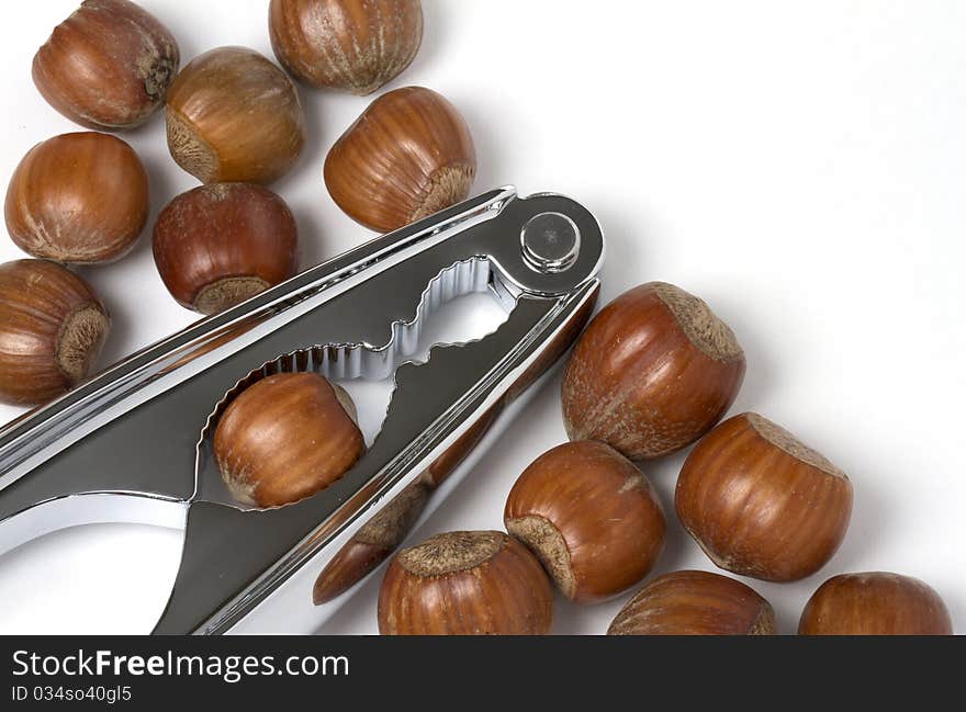 Hazel nuts with chrome nut crackers on white background. Hazel nuts with chrome nut crackers on white background